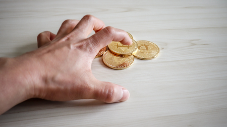 A hand trying to grab a bitcoin strongly.の写真素材