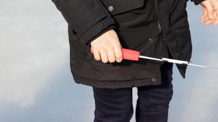 Trout Ice fishing festival at the winter. The woman's hand with a fishing rod in its hand.