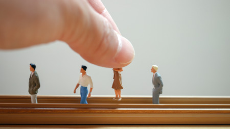 Men and women of miniature. The hand holding the woman in between the men.の写真素材