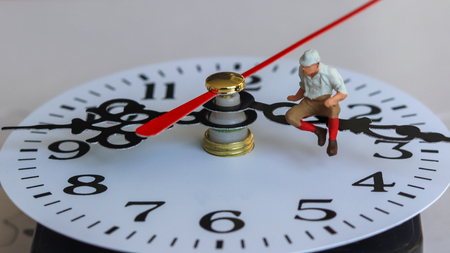 A miniature man sitting on a watch needle.の写真素材