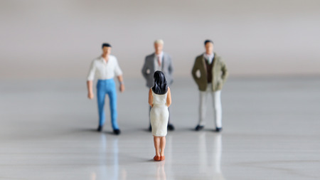 Three miniatures men and one miniature woman face each other.の写真素材