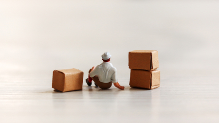 A miniature man sitting on a paper box.の写真素材