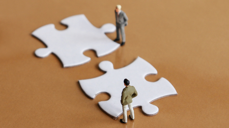 Two miniature people and two puzzle pieces.の写真素材