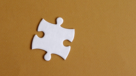 A piece of a puzzle on a light brown background.の写真素材