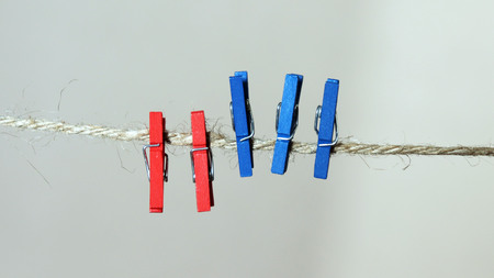 Three blue laundry clips and two red laundry clips on a rope.の写真素材