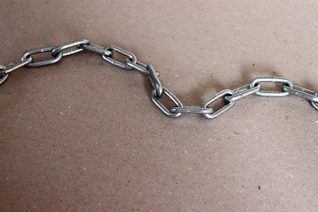 A silver metal chain lying on the floorの写真素材