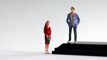 Miniature men and women standing at different heights.の写真素材