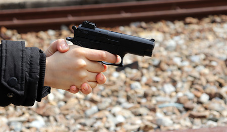 A woman's hand pointing a gun. Concept of risk of possessing an illegal weapon.