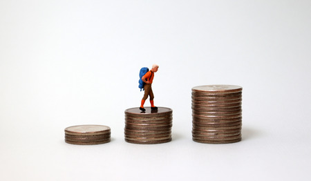 A miniature man climbing a pile of coins.の写真素材