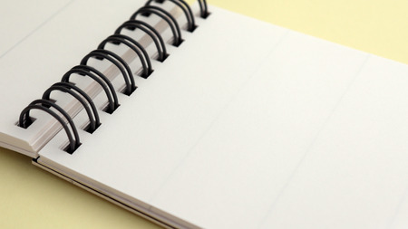 Wire bound notebook pad isolated on soft yellow background.