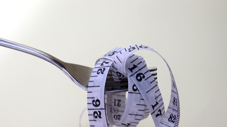 A fork with a tape measure rolled up.の写真素材