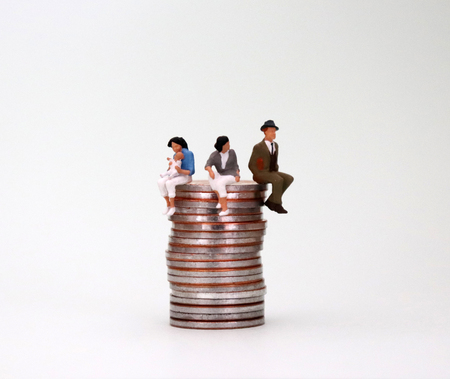 The concept of equal work and equal pay. A pile of coins and miniature people.の写真素材