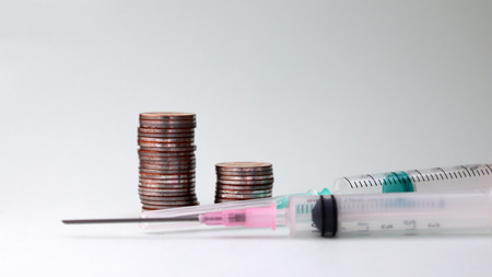 A pile of disposable medical syringes and coins. The concept of increasing the cost of personal burden health care.の写真素材