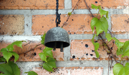 Metallic wind-bell on the red brick wall.の写真素材