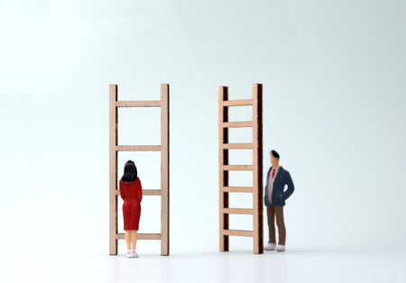 Miniature men and women standing in front of different ladders. The concept of gender differentiation between promotion and employment.の写真素材
