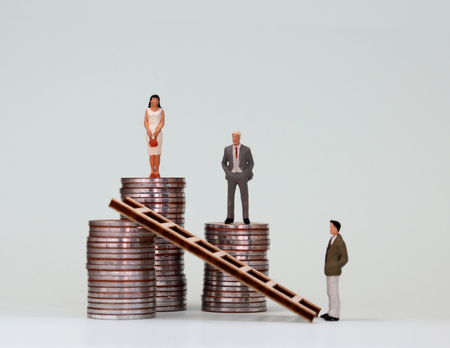 The concept of women's leadership. A miniature woman standing on a pile of the highest coins.の写真素材