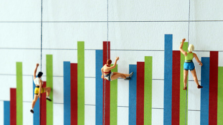 Miniature people climbing up a bar graph. A concept of difficulty in employment.の写真素材