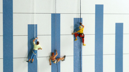 The miniature climbers use a rope to climb the blue bar graph. The concept of youth dreaming of social success.の写真素材