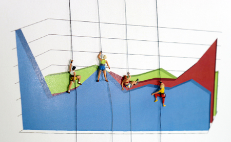 The miniature climbers use a rope to climb the three dimensions area graph. Efforts and competitive concepts to achieve business results.の写真素材