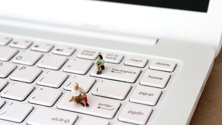 A miniature woman sitting on the backspace key and a miniature man sitting on the enter key. A sexist concept of the company system.の写真素材
