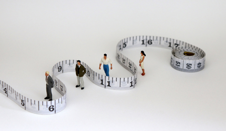 White tape measure with miniature people. The concept of gender promotion discrimination.の写真素材