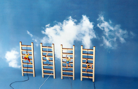 Miniature climbers climbing a wooden ladder against the backdrop of the blue sky. Competitive social concept.の写真素材