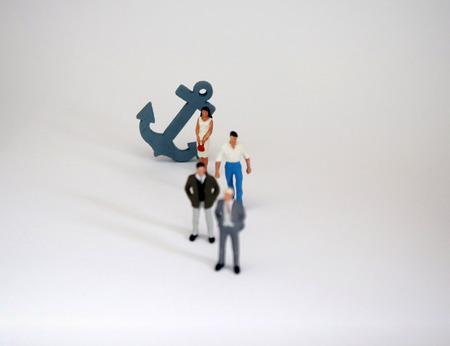 Three miniature men and a gray anchor with a miniature woman. The male-centric concept of power in business.の写真素材