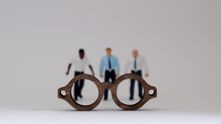 A social prejudice against race. Miniature people standing behind wooden miniature glasses.の写真素材