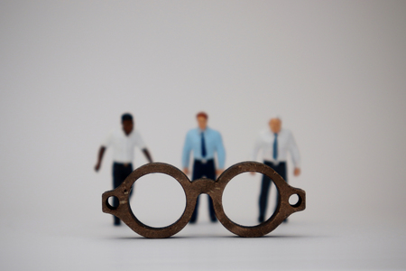 The concept of racist views. Miniature people standing behind wooden miniature glasses.の写真素材