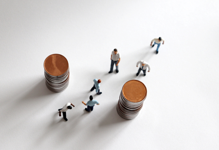 The concept of busy workers. Pile of coins and busy walking miniature people.
