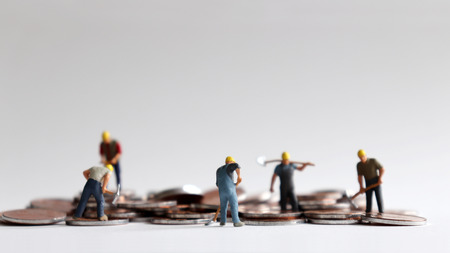 The workers are working hard money. Coins and miniature people.の写真素材