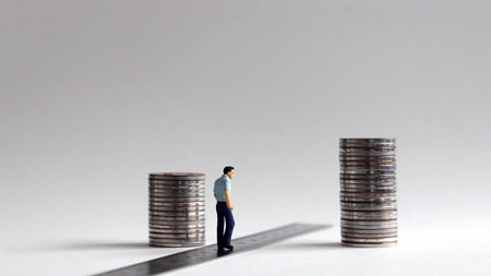 Miniature people with two stacks of coins.の写真素材