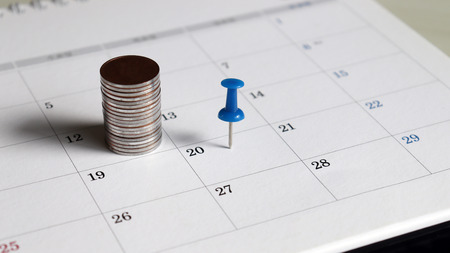 A pile of coins and a blue tack on the calendar.