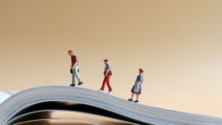 Miniature people walking on open pages.