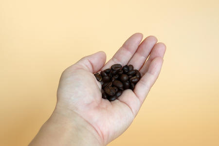 roasted coffee beans on the palm of one's handの写真素材