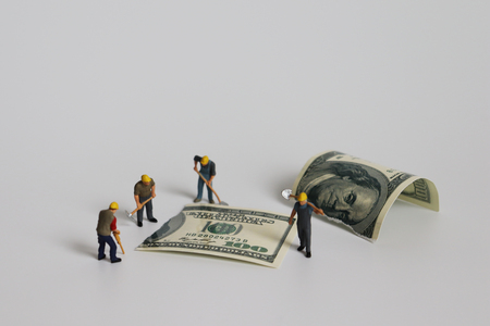 A hundred dollar bill torn in half with miniature worker. Concepts on financial crisis management.の写真素材