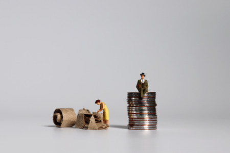 A pile of coins and miniature people. A concept of profit and poverty.の写真素材