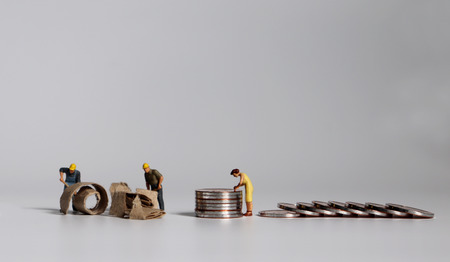 A pile of coins and miniature people.の写真素材
