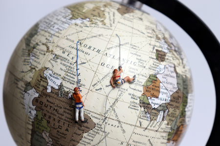 Two miniature climbers clinging to the globe.の写真素材