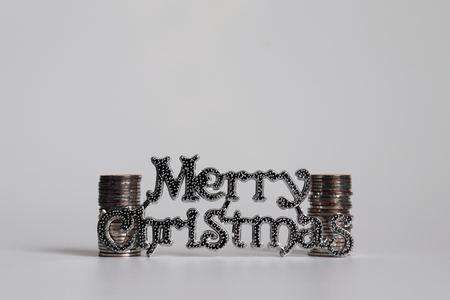 Text Merry Christmas and two pile of coins.の写真素材