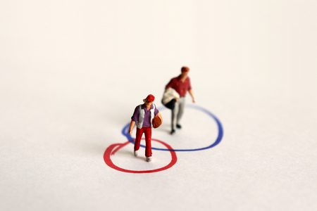 A miniature woman and a miniature man on the two overlapping circles in the other.の写真素材