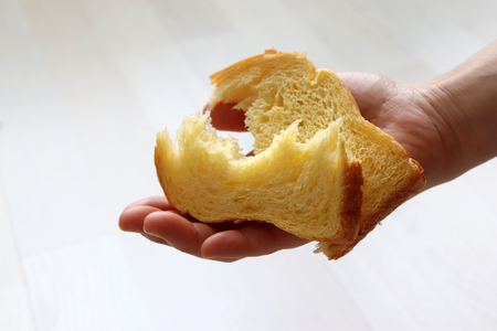 A torn bread on the palm of a woman.の写真素材