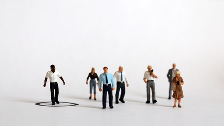 A miniature black man standing in a black circle and a miniature people outside the circle.の写真素材