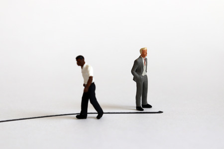 The concept of racial conflict. A miniature black man and a miniature white man standing back from each other with boundaries between them.の写真素材