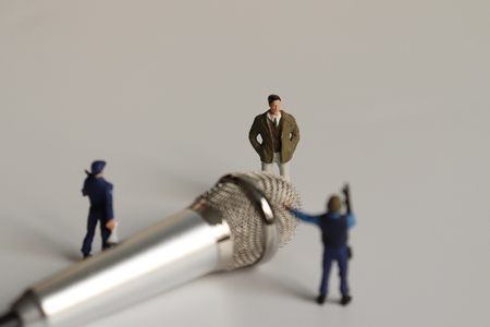 Miniature people and a microphone.の写真素材