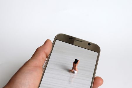 The back of a miniature woman who is changing their clothes. Miniature people and Smartphone.の写真素材