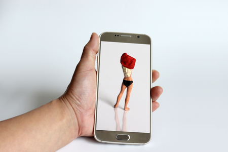 Secret camera concept of social crime. The back of a miniature woman who is changing clothes and a Smartphone.の写真素材