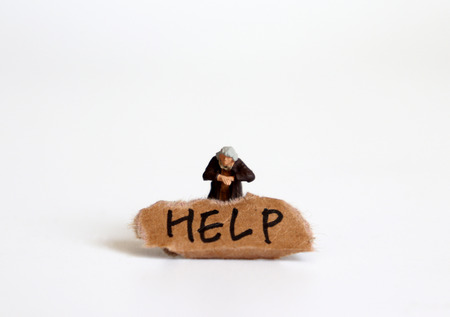 The concept of gap between rich and poor. A letter of HELP on a torn piece of paper with a miniature woman.の写真素材