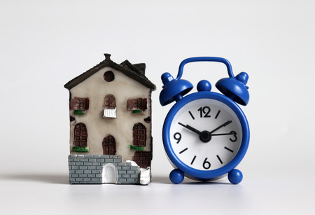 A miniature house and a blue alarm clock.
