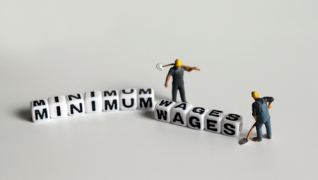 'MINIMUM WAGES' word in white cube. Miniature people.の写真素材